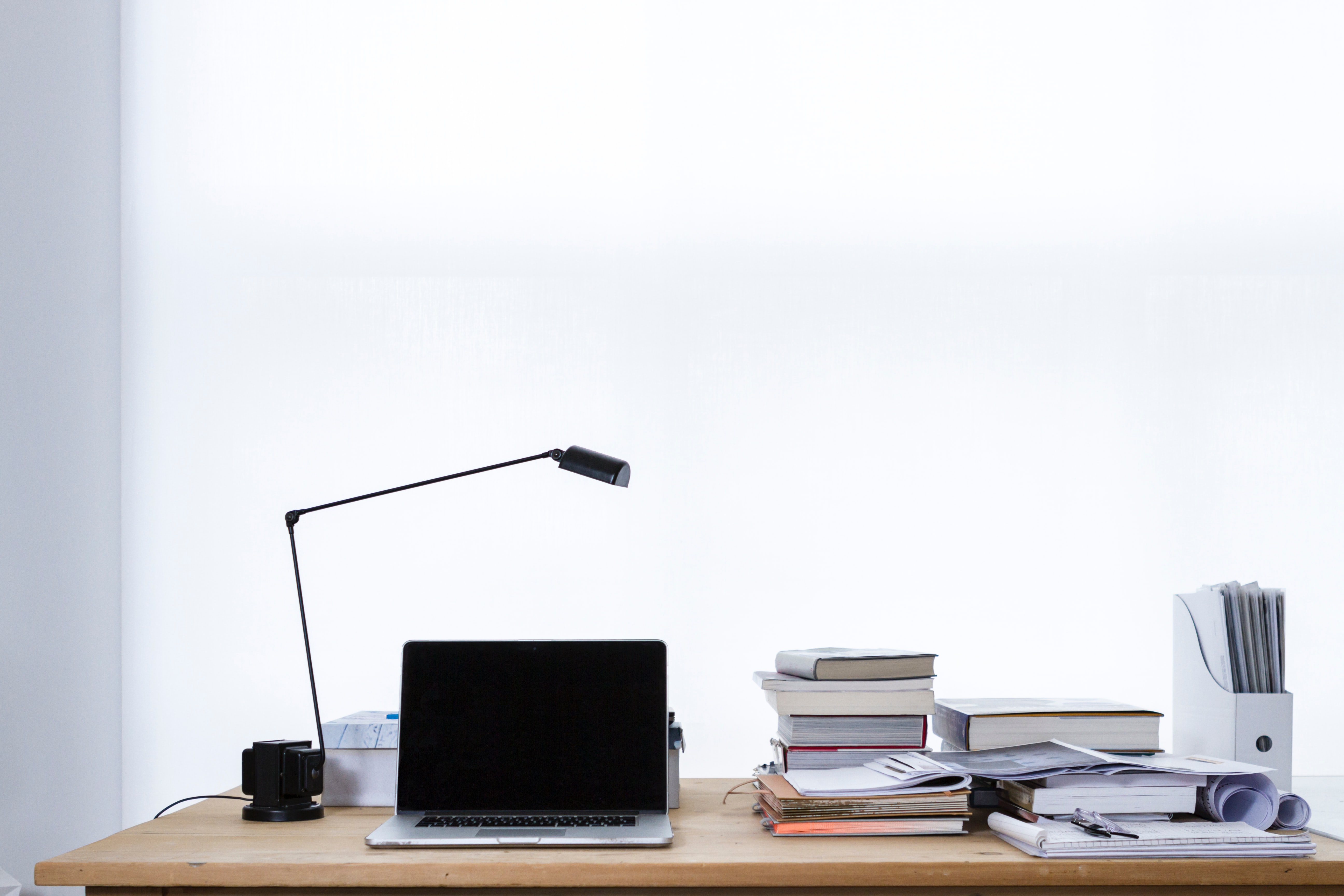 A computer on a desk with a stack of books